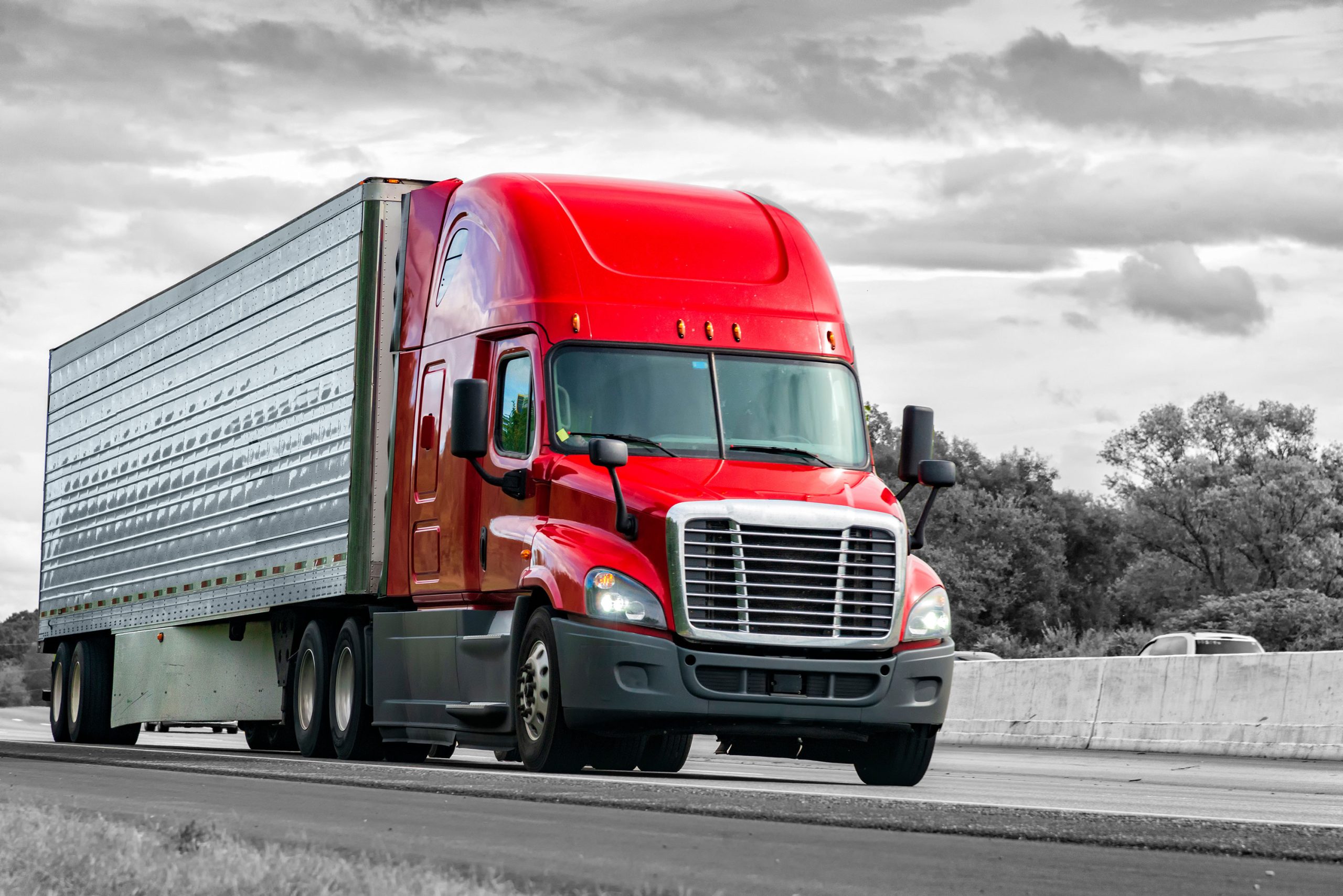 Low-angle photo of red semitruck driving on the highway.
