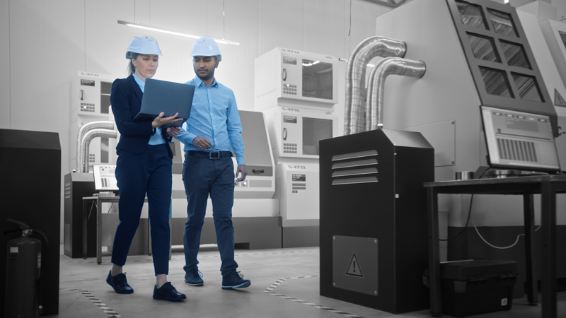 Two people walking through a modern plastics extruding or molding plant.