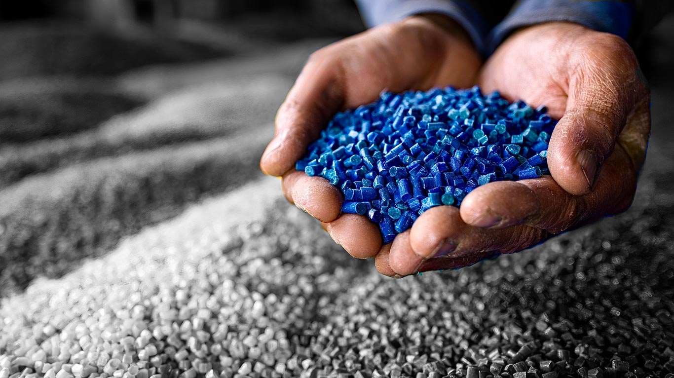 Experienced hands holding blue color concentrate pellets.